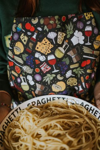 woman serving spaghetti in a black Italian food apron